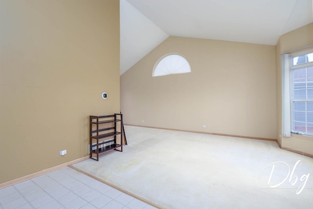 spare room featuring baseboards, lofted ceiling, and light colored carpet