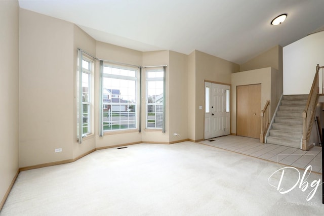 carpeted foyer entrance with baseboards, vaulted ceiling, stairway, and visible vents