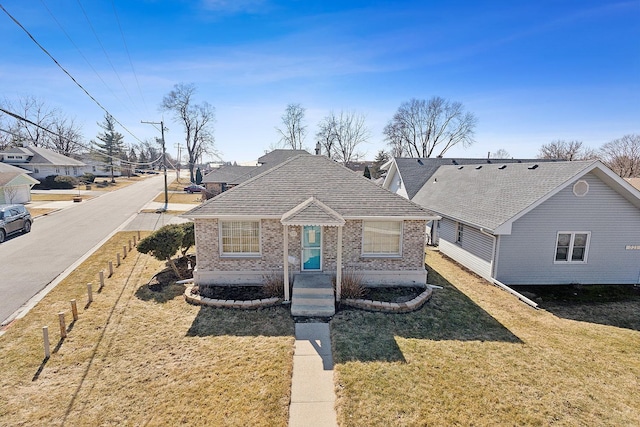 bungalow-style home with a front yard, brick siding, and roof with shingles