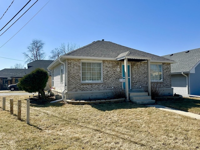 view of front facade featuring brick siding, roof with shingles, and a front lawn