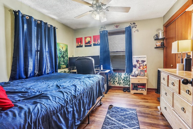 bedroom with baseboards, a textured ceiling, wood finished floors, and a ceiling fan