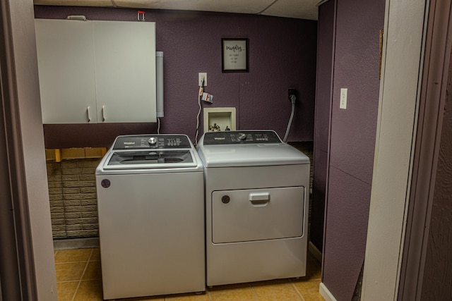 washroom featuring light tile patterned floors, cabinet space, independent washer and dryer, and a textured wall