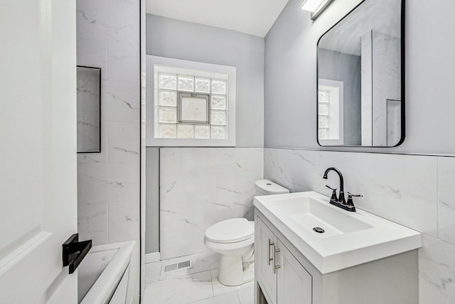 full bathroom featuring visible vents, tile walls, toilet, marble finish floor, and vanity