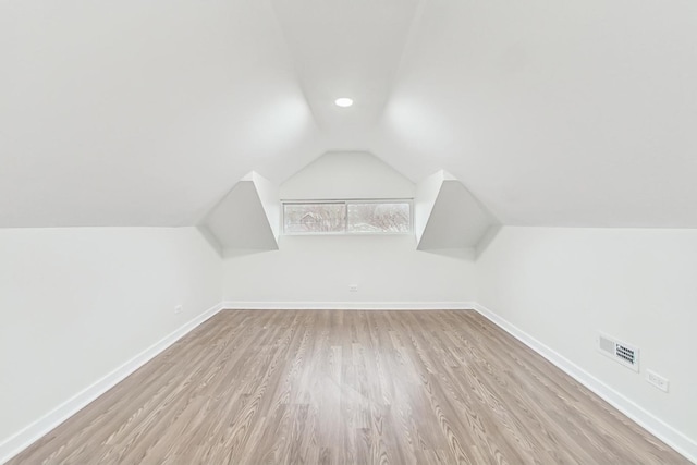 additional living space featuring wood finished floors, baseboards, visible vents, and lofted ceiling