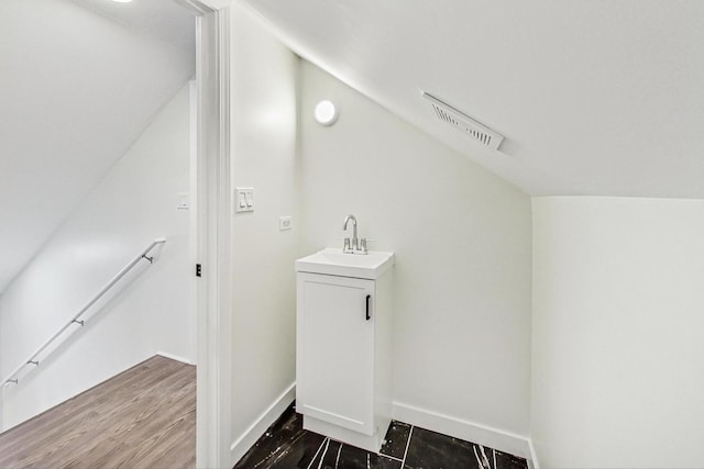 interior space featuring a sink, visible vents, baseboards, and wood finished floors