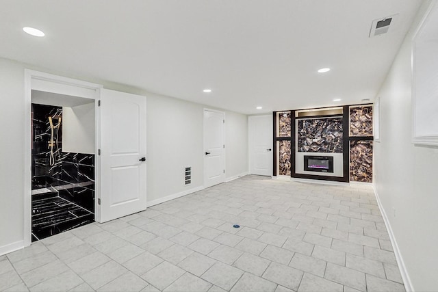 finished below grade area with a glass covered fireplace, recessed lighting, baseboards, and visible vents