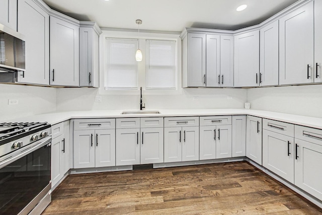 kitchen featuring pendant lighting, a sink, appliances with stainless steel finishes, light countertops, and dark wood-style flooring