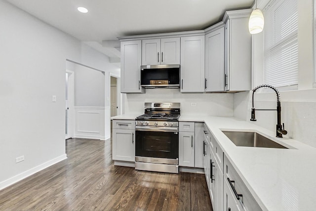 kitchen with a sink, dark wood-type flooring, light countertops, and stainless steel appliances