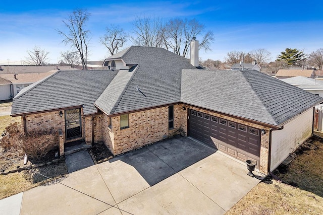 view of front of home with roof with shingles, concrete driveway, an attached garage, brick siding, and a chimney