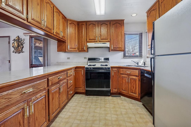 kitchen with under cabinet range hood, black dishwasher, gas range oven, freestanding refrigerator, and a sink