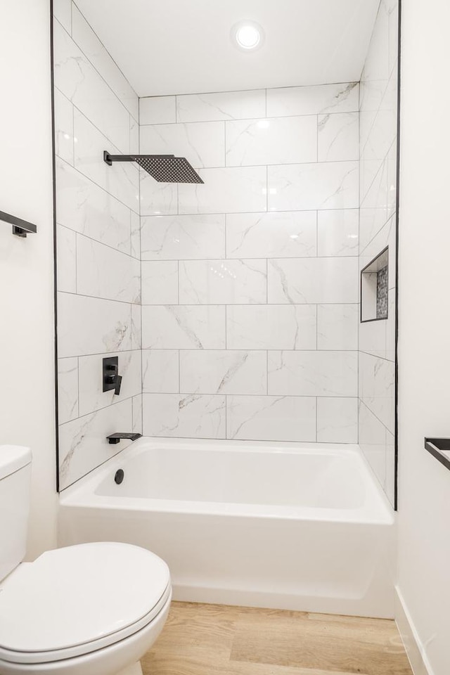 bathroom with shower / washtub combination, toilet, baseboards, and wood finished floors