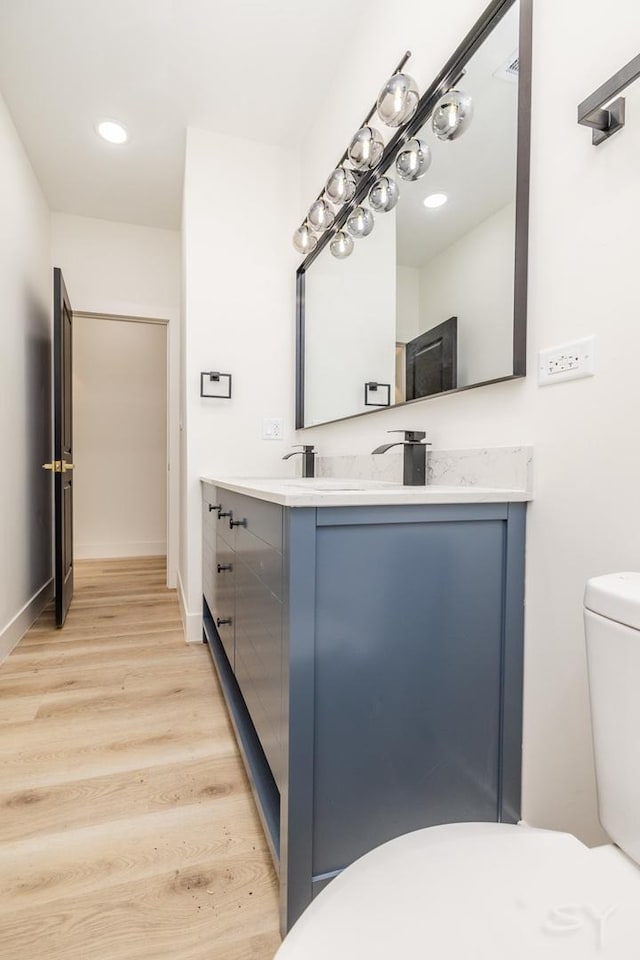 bathroom with vanity, wood finished floors, baseboards, recessed lighting, and toilet