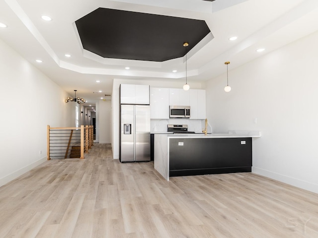 kitchen featuring light wood-type flooring, white cabinets, stainless steel appliances, a raised ceiling, and modern cabinets