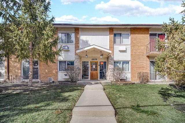 multi unit property with a front lawn, cooling unit, and brick siding