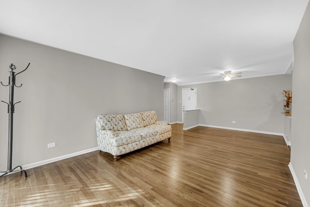 living area featuring ceiling fan, baseboards, and wood finished floors