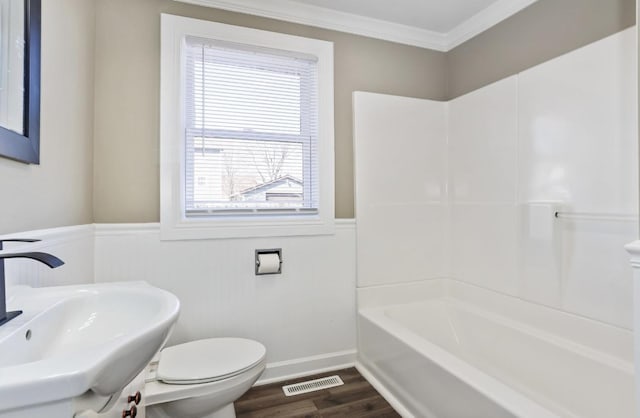 bathroom with visible vents, toilet, a sink, wood finished floors, and crown molding