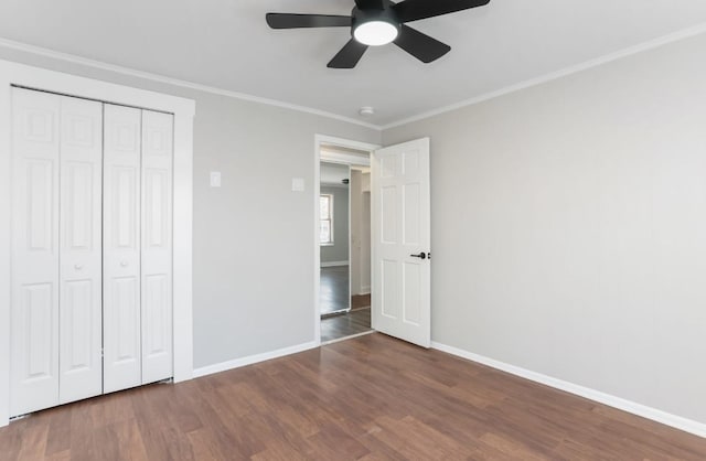 unfurnished bedroom featuring ornamental molding, a ceiling fan, wood finished floors, a closet, and baseboards