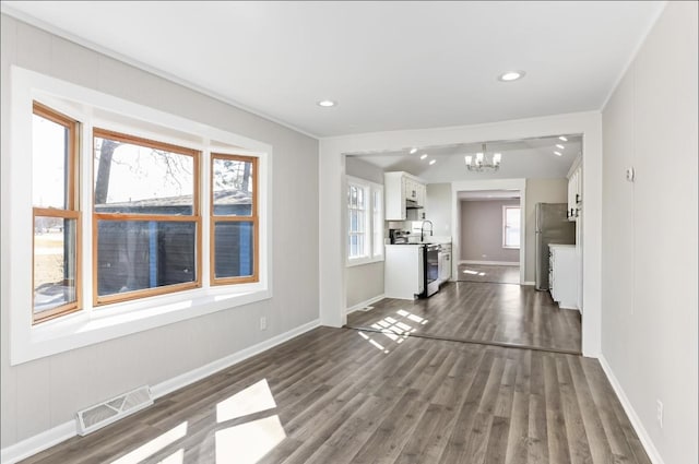 unfurnished living room with visible vents, dark wood-type flooring, baseboards, a chandelier, and recessed lighting