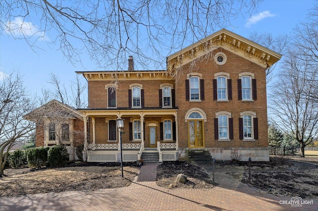 italianate-style house featuring brick siding, covered porch, and a chimney