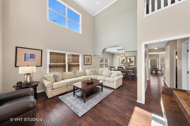 living area featuring baseboards, arched walkways, dark wood-type flooring, and a chandelier