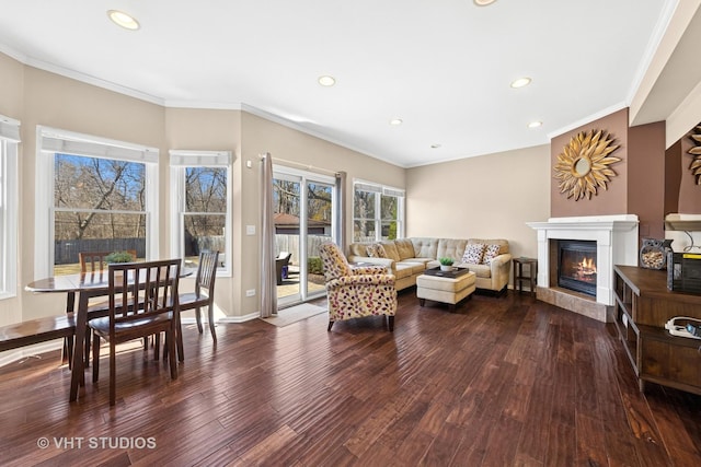 living area featuring a glass covered fireplace, wood finished floors, recessed lighting, and ornamental molding