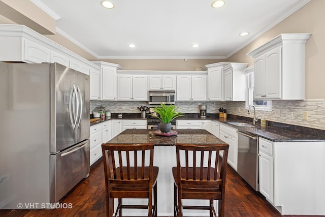 kitchen featuring dark wood-type flooring, a breakfast bar, a sink, stainless steel appliances, and white cabinets