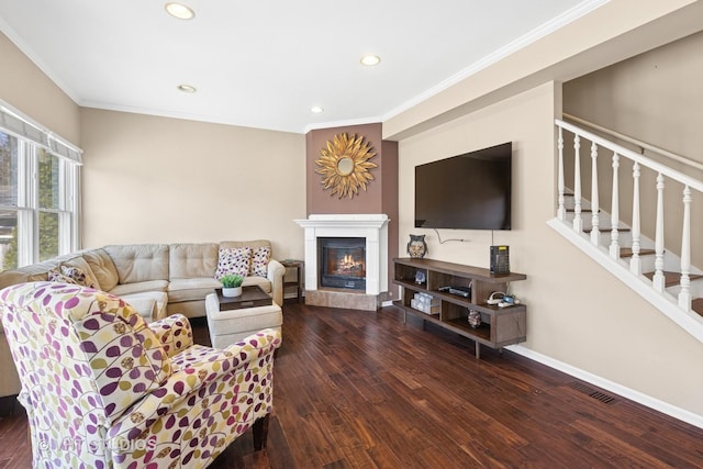 living area with wood finished floors, baseboards, recessed lighting, a glass covered fireplace, and crown molding