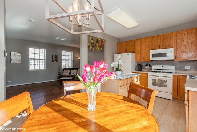 dining space featuring light tile patterned floors, baseboards, and an inviting chandelier