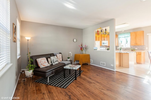 living room featuring visible vents, baseboards, and wood finished floors