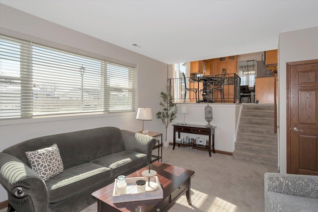 living area with stairway, light colored carpet, and visible vents