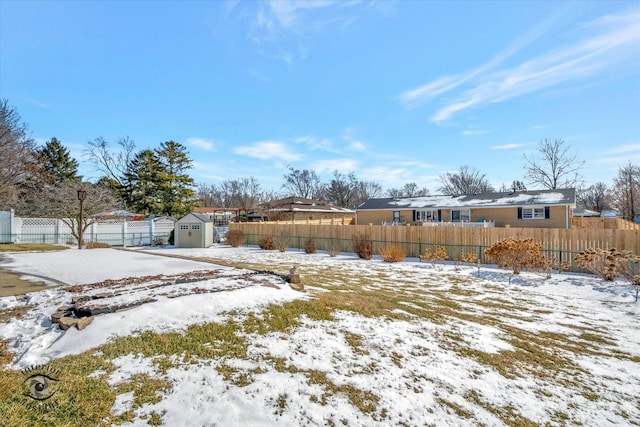 yard layered in snow with an outbuilding, a storage unit, and fence private yard