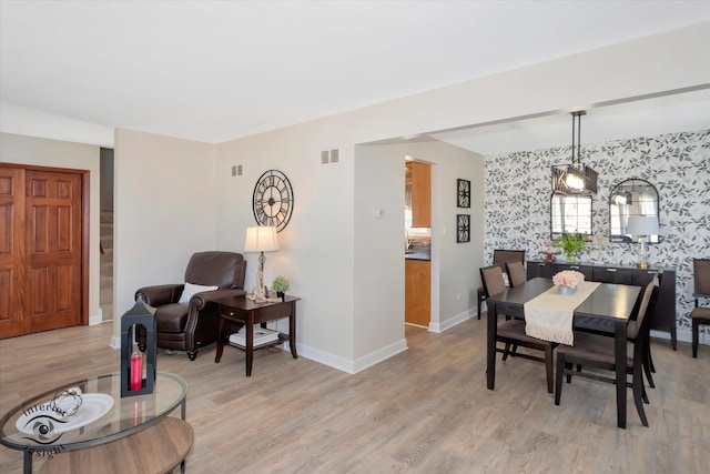 dining space featuring visible vents, light wood-style flooring, wallpapered walls, baseboards, and stairs