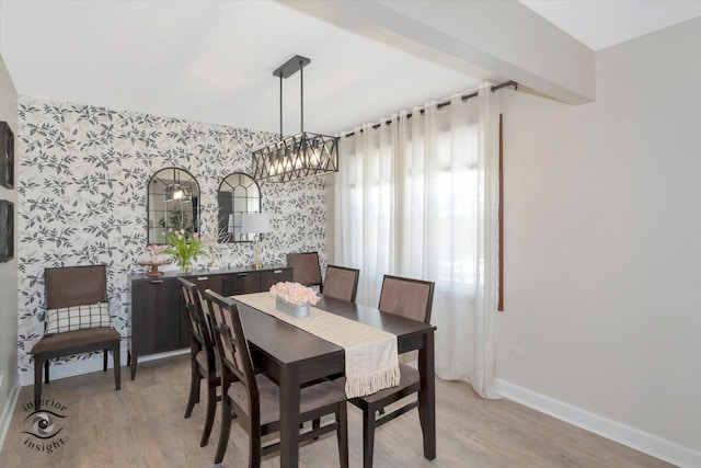 dining area with light wood finished floors, wallpapered walls, and baseboards