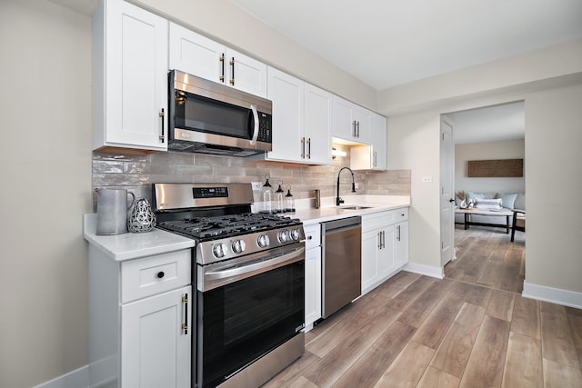 kitchen featuring a sink, decorative backsplash, light countertops, and stainless steel appliances