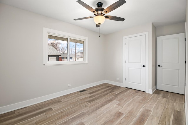 unfurnished bedroom featuring visible vents, light wood-style flooring, a ceiling fan, and baseboards