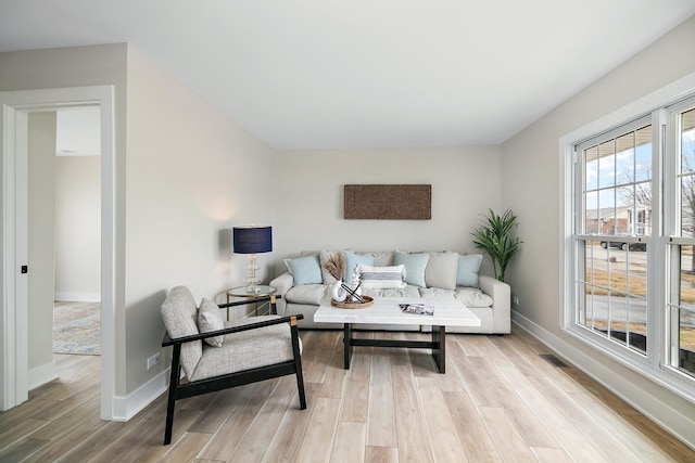 living area with light wood-style floors, visible vents, and baseboards