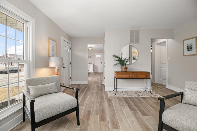 sitting room featuring light wood-type flooring, visible vents, and baseboards