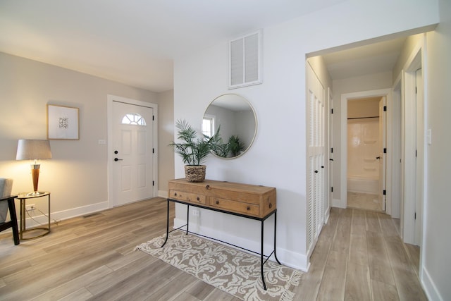 foyer entrance featuring visible vents, light wood-style flooring, and baseboards