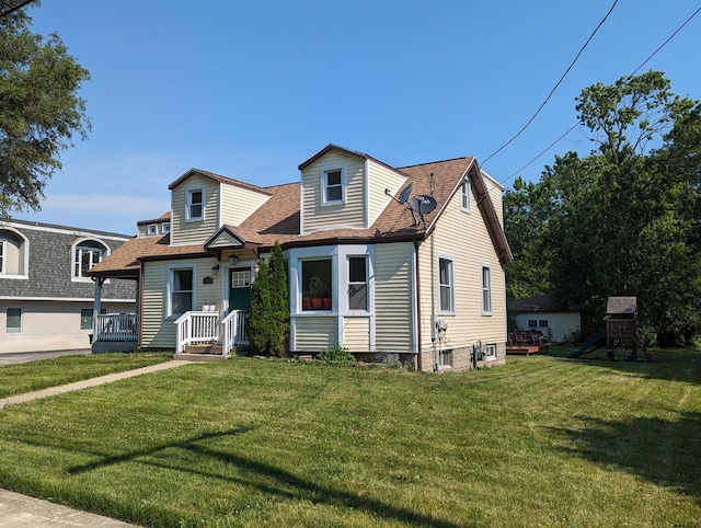 view of front of house featuring roof with shingles, a front yard, and a playground