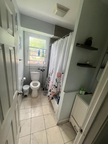 full bathroom with tile patterned floors, visible vents, curtained shower, and toilet