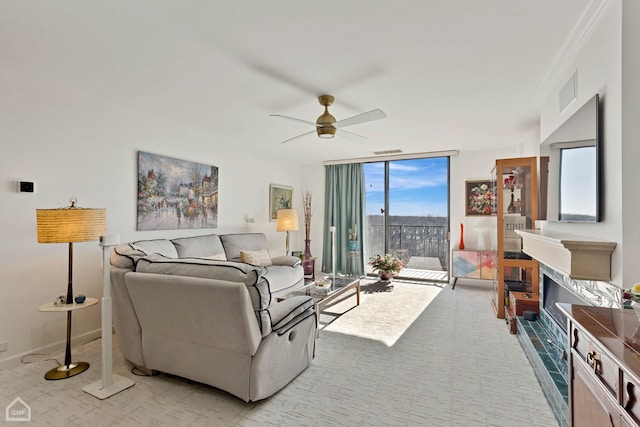 living room featuring visible vents, a wall of windows, baseboards, light colored carpet, and ceiling fan