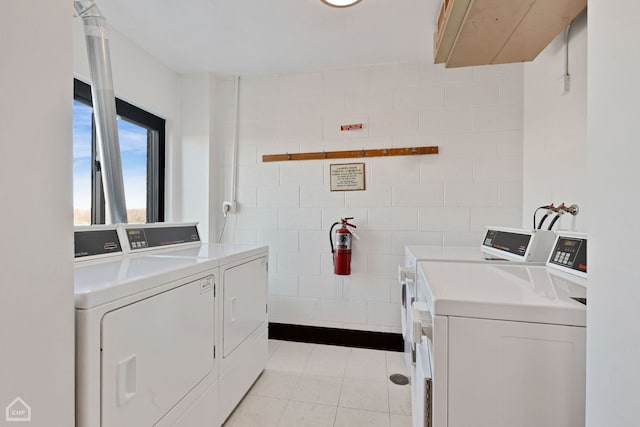 common laundry area featuring washing machine and clothes dryer, tile walls, and light tile patterned flooring