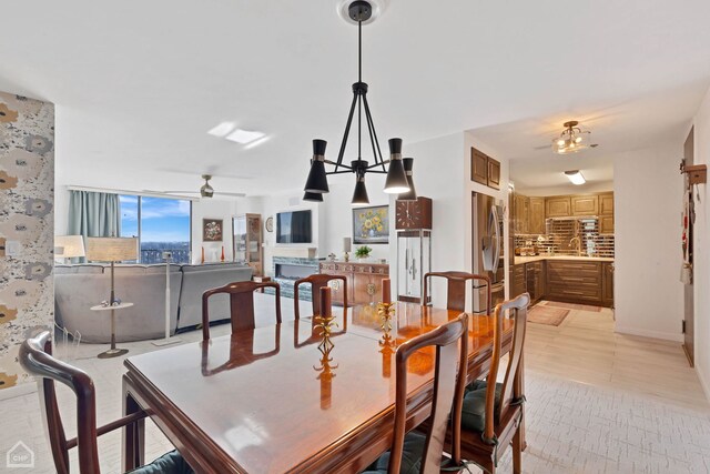 dining room featuring light tile patterned floors, ceiling fan with notable chandelier, and a fireplace