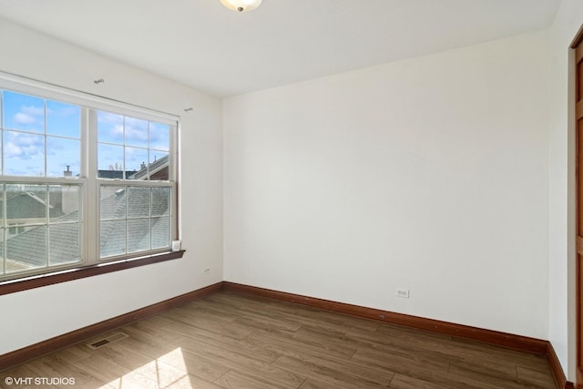 unfurnished room with visible vents, baseboards, and wood finished floors