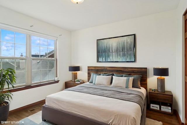 bedroom with visible vents, wood finished floors, and baseboards