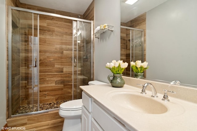 bathroom with a stall shower, toilet, vanity, and wood finished floors