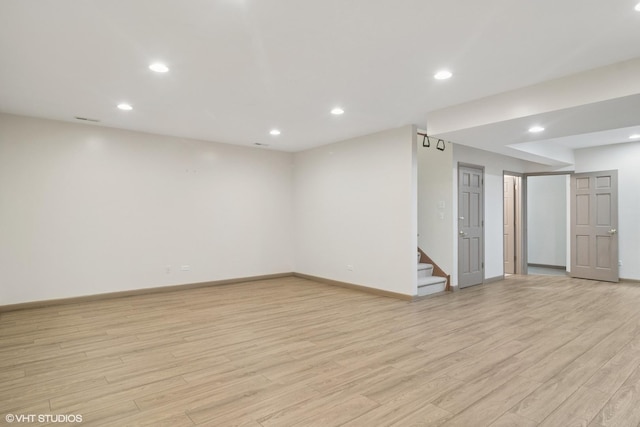 spare room featuring stairway, recessed lighting, light wood-type flooring, and baseboards