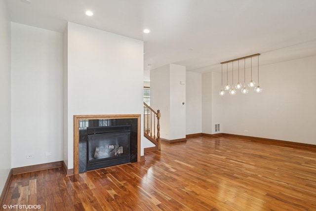 unfurnished living room featuring a glass covered fireplace, baseboards, hardwood / wood-style floors, and recessed lighting