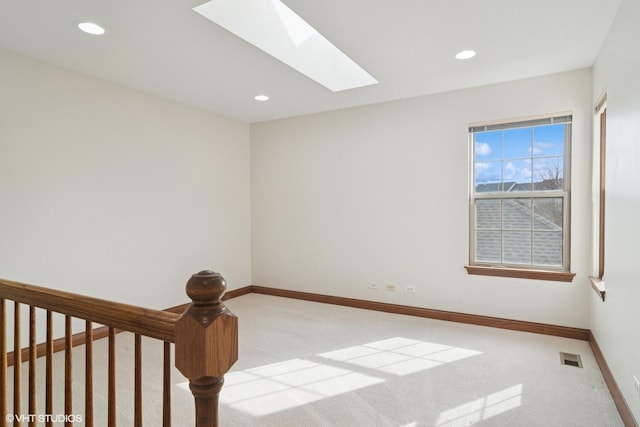 unfurnished room with a skylight, baseboards, and carpet floors