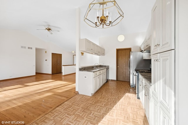 kitchen with ceiling fan with notable chandelier, a sink, open floor plan, stainless steel appliances, and parquet flooring